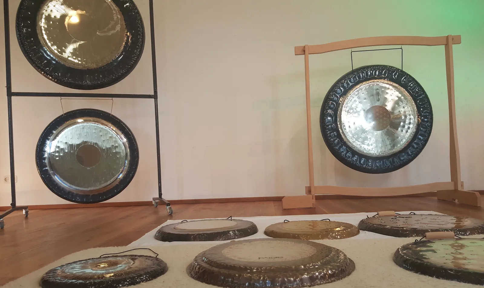 Gong-Studio mit mehreren Gongs auf Ständern und am Boden, der große Gong am hellen Holz-Bogenständer