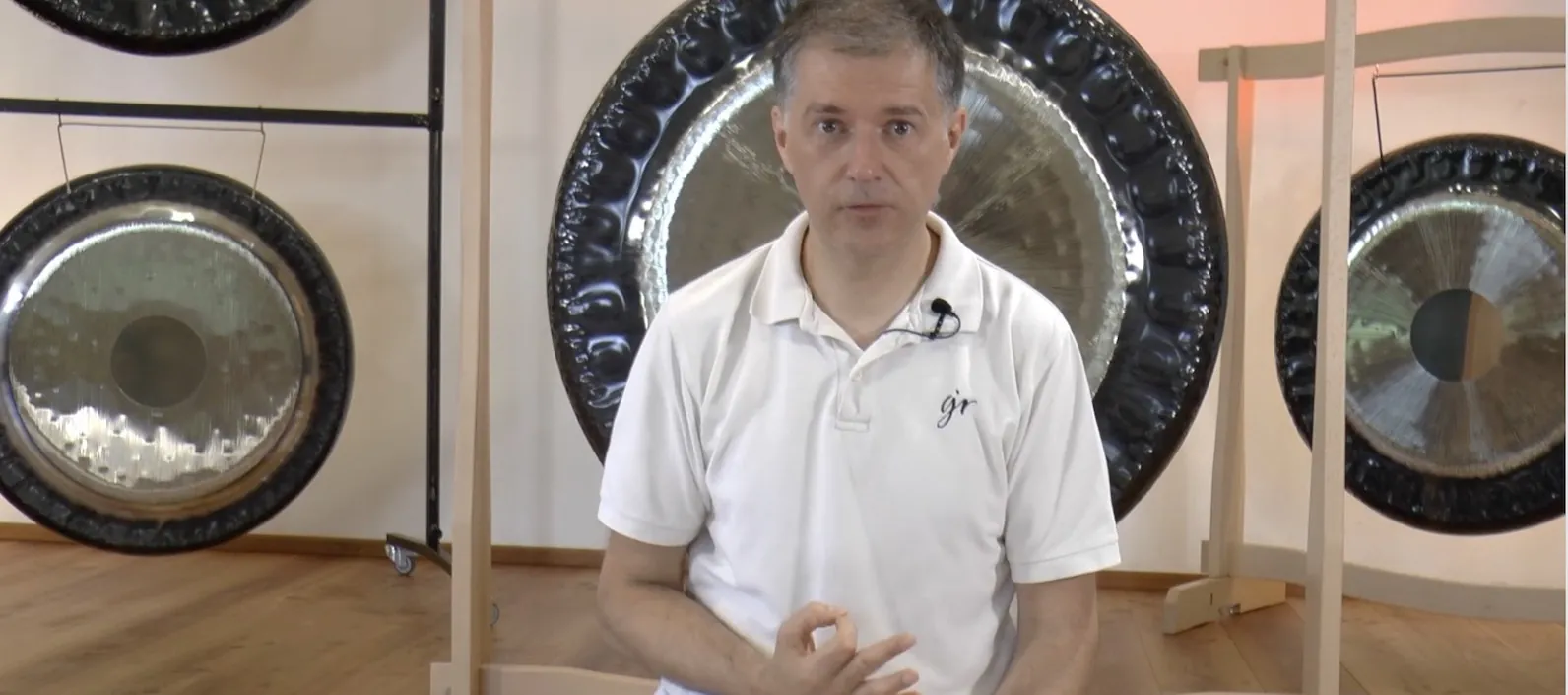 Alexander Renner erklärt vor der Kamera im Online-Kurs, hinter ihm mehrere Gongs