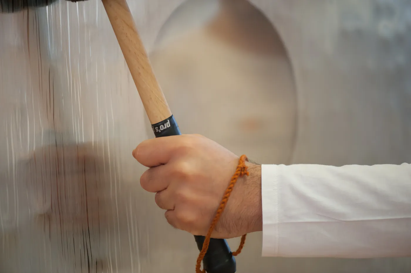 Hand mit Mala führt das Mallet über einen Gong