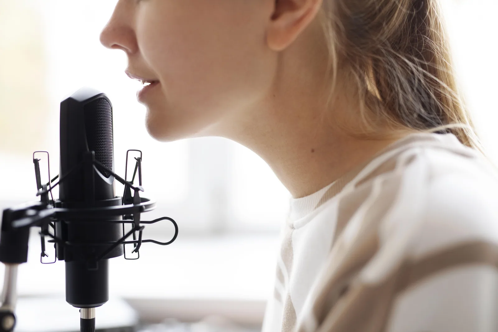 Frau spricht aus der Nähe in ein Studiomikrofon, helles Tageslicht
