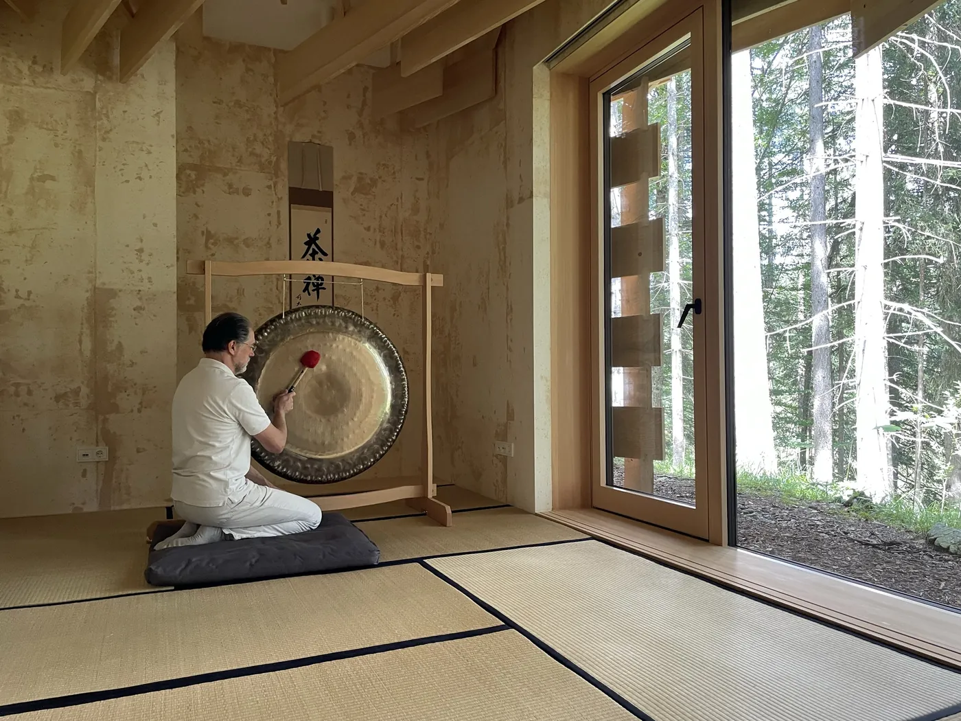 Alexander Renner am Gong in einem Zen-Raum mit Tatami und Kalligrafie