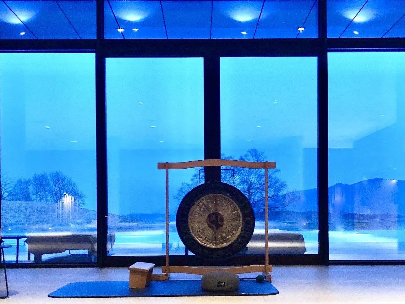 Raum in blauem Abendlicht mit Gong und Kerzen vor einer Fensterfront